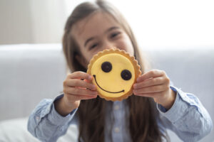 Imagem de criança segurando um biscoito com uma carinha feliz